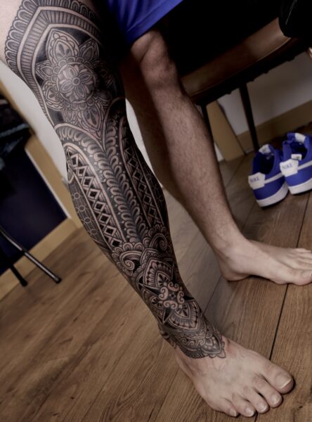 A man's leg with ornamental blackwork and geometric tattoo designs
