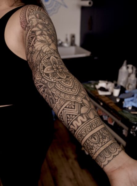 Ornamental and flower and mandala tattoos on a woman's arm